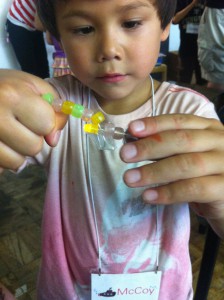 Benjiro learns about monomers and polymers through hands-on play with beads at Mini Mad Scientists Camp.
