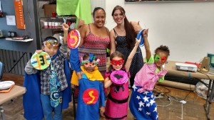 The children dressed in superhero costumes, and posing along with Angel and Fabienne.